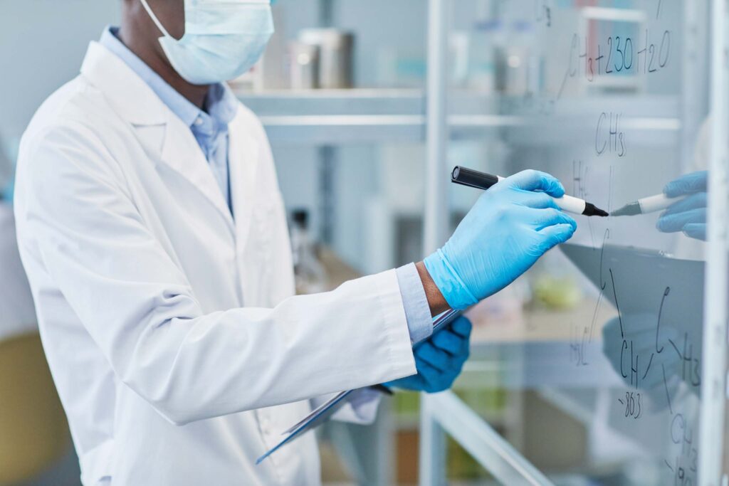 chemist writing chemical formulas on whiteboard