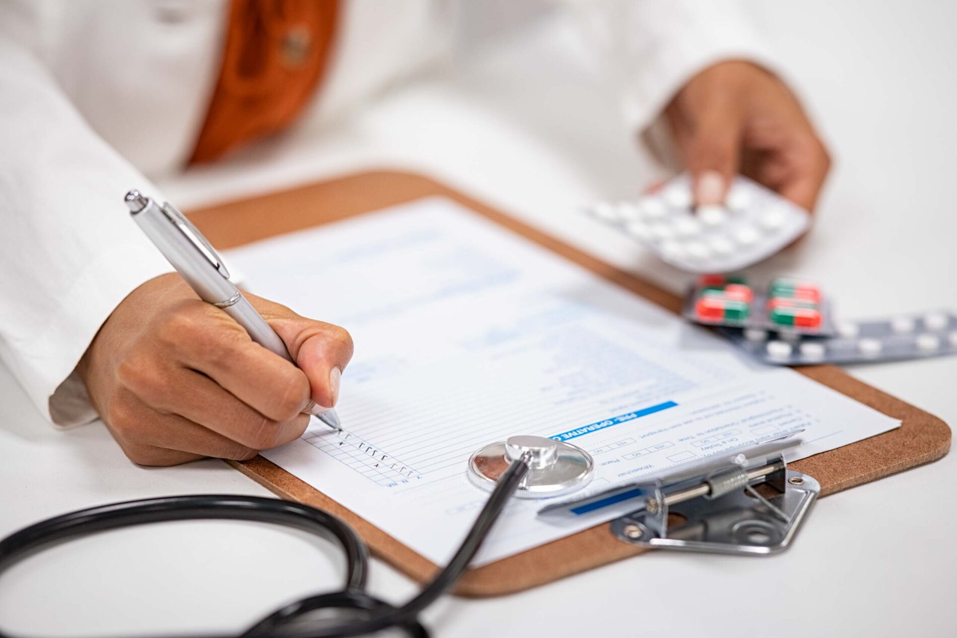 close up of doctor writing on clipboard